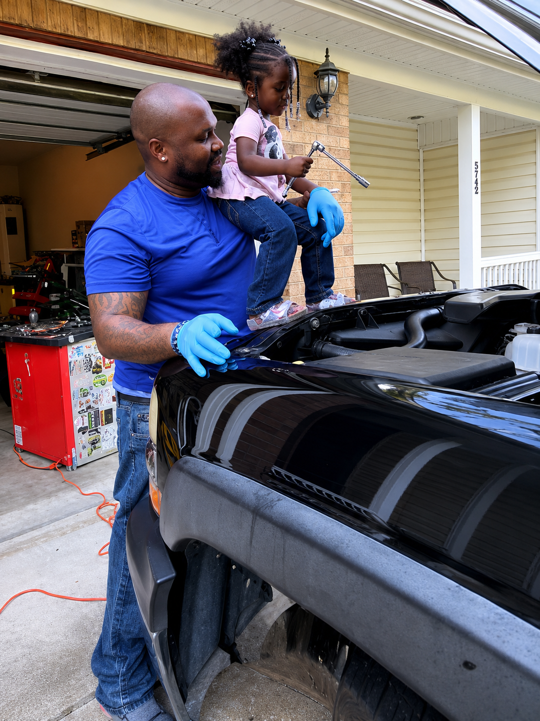 Mizell's owner working on a vehicle with his daughter sitting on the hood